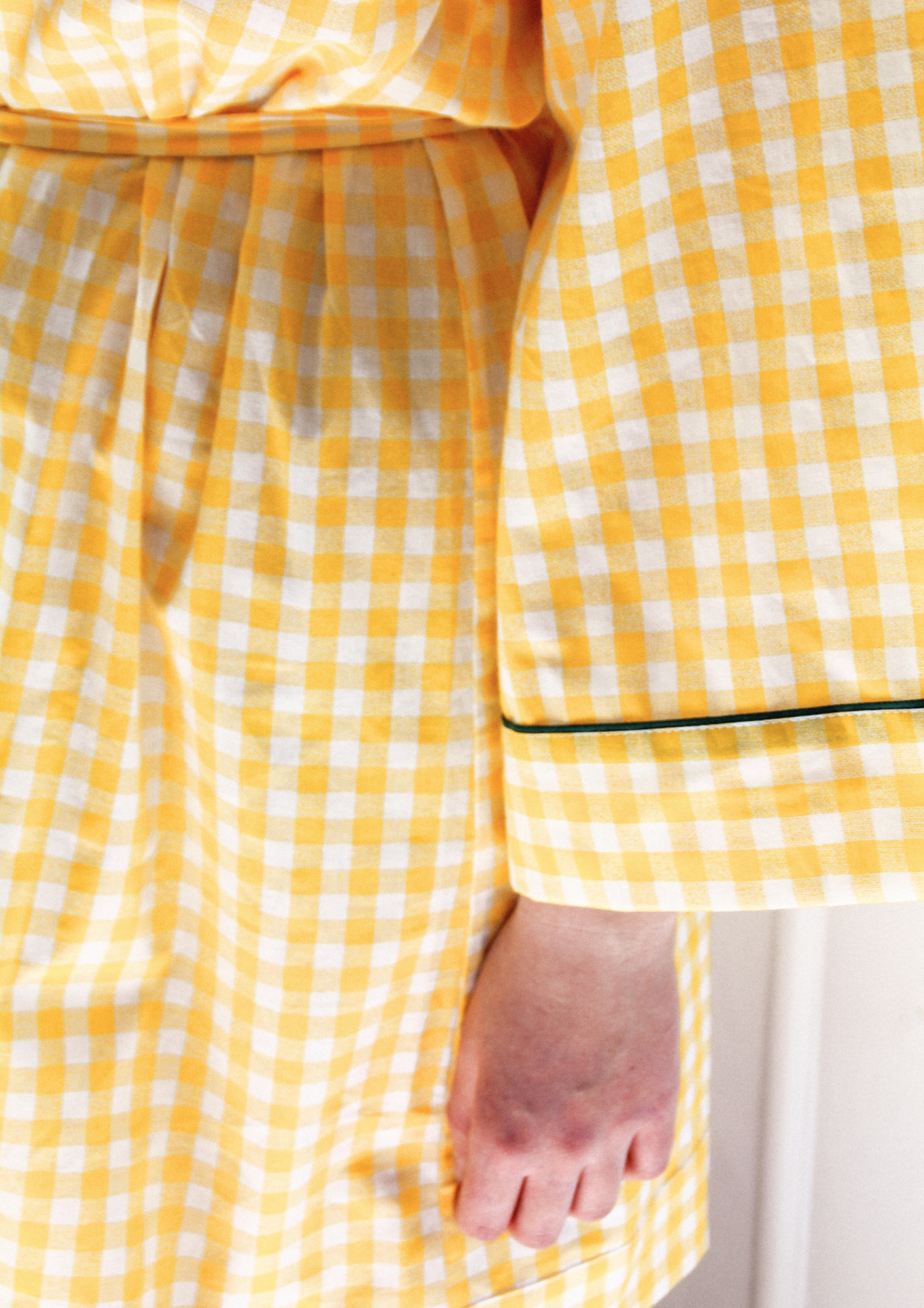 Femme portant un kimono court en coton vichy jaune à passepoil vert, noué à la taille, dans une pièce lumineuse.