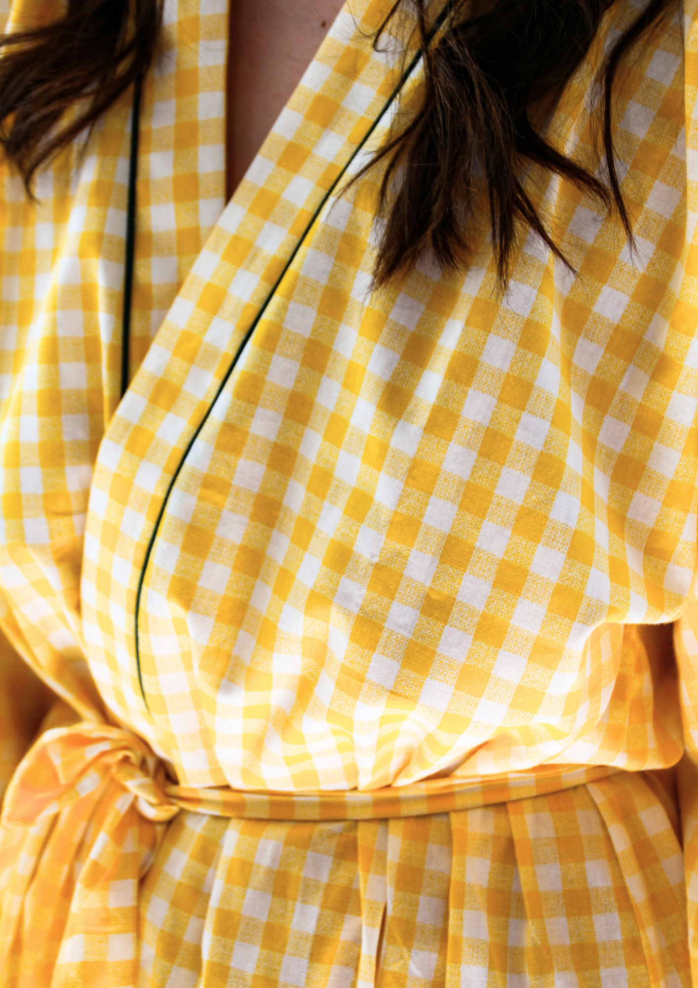 Femme portant un kimono court en coton vichy jaune à passepoil vert, noué à la taille, dans une pièce lumineuse.