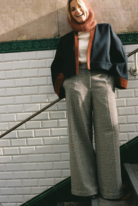 Femme portant le kimono VÉRO Atelier Sarita, un kimono court en laine noire caviar avec finitions en velours coton couleur oud, photographié dans une entrée de métro parisien. Modèle au style architectural et urbain, confectionné à la main à Paris.