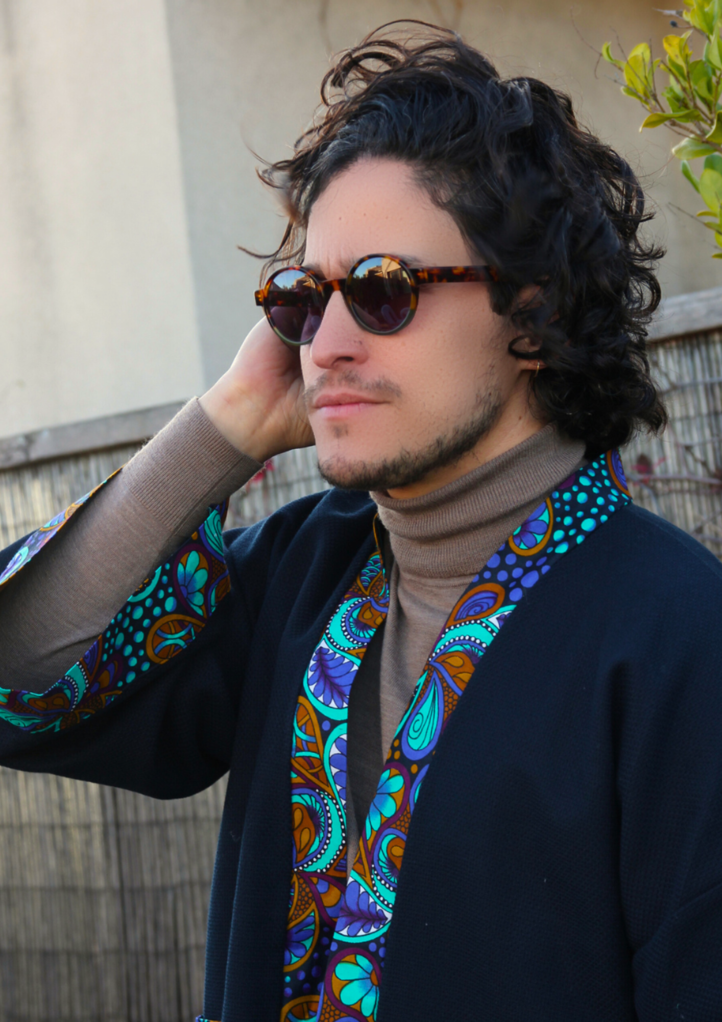 Homme portant un kimono court en coton bleu avec finitions en wax coloré, manches larges et poches assorties.