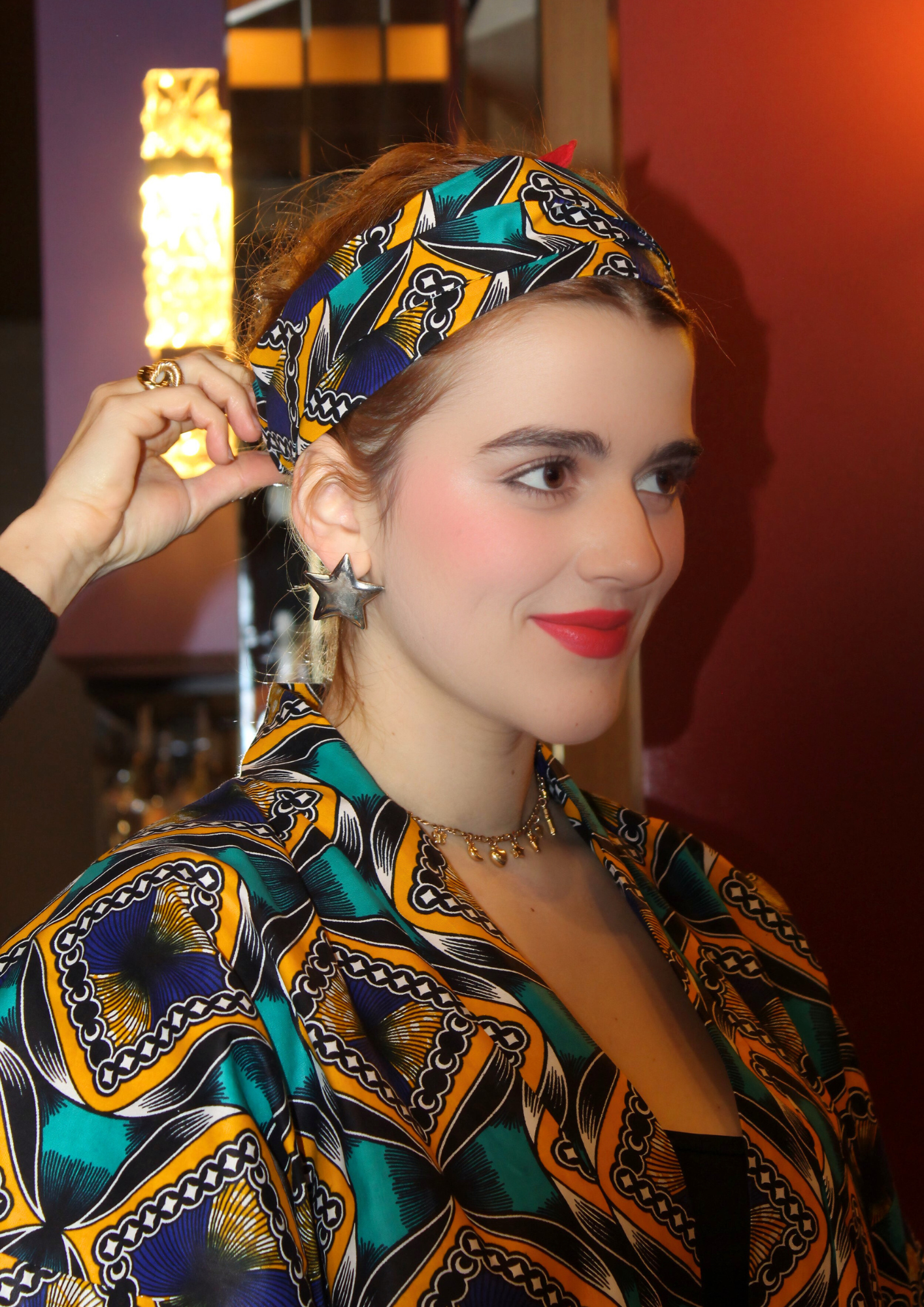 Jeune femme vêtue d'un kimono en wax lifestyle, avec la ceinture du kimono nouée dans les cheveux.