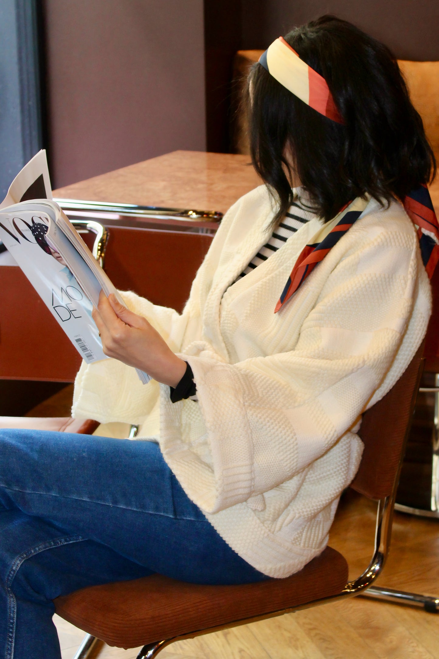 Jeune femme au look retro porte un kimono en laine blanc cassé, doux et élégant, idéal pour les douces journées printanières. Cette pièce unique est confectionnée à la main avec soin à Paris.