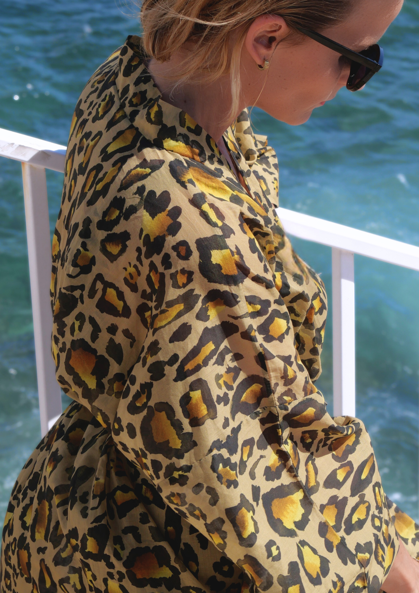 Femme portant un kimono long en voile de coton à imprimé léopard, ceinturé à la taille, posant face à la mer sous le soleil – création Atelier Sarita, confectionnée à la main à Paris.