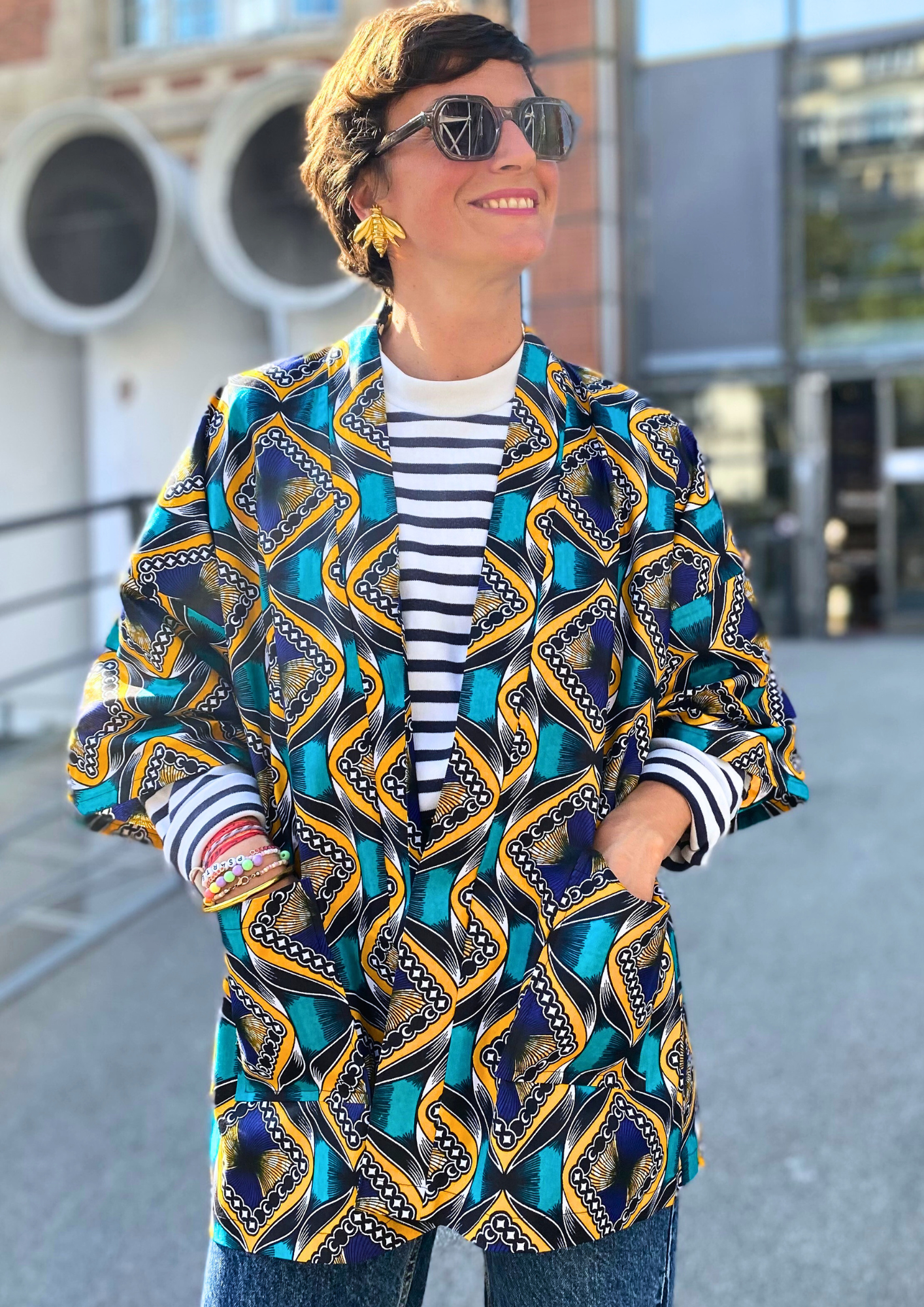 Jeune femme vêtue d'un kimono en wax lifestyle porté comme une veste en plein cœur de Paris.