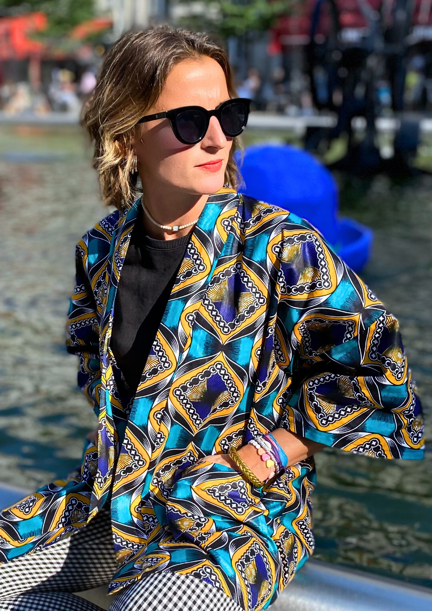 Jeune femme vêtue d'un kimono en wax lifestyle porté comme une veste en plein cœur de Paris.