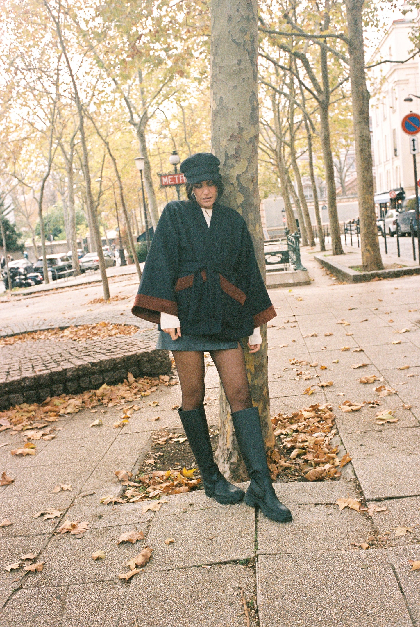 Femme portant le kimono DODAT Atelier Sarita, un kimono veste en laine caviar noire avec finitions en velours coton couleur oud, photographié en extérieur au soleil. Modèle unisexe, confectionné à la main à Paris, au style urbain et architectural.