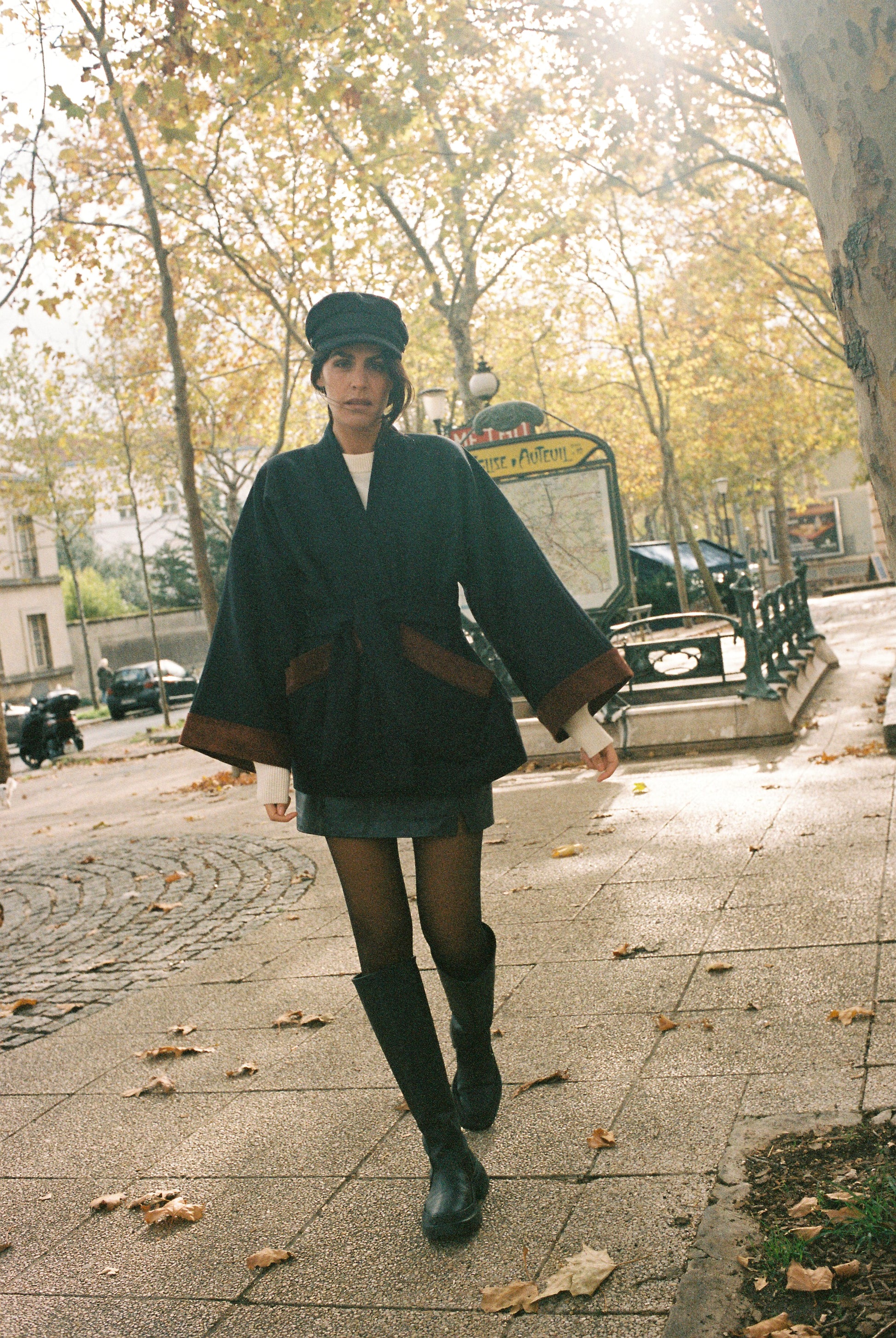 Femme portant le kimono DODAT Atelier Sarita, un kimono veste en laine caviar noire avec finitions en velours coton couleur oud, photographié en extérieur au soleil. Modèle unisexe, confectionné à la main à Paris, au style urbain et architectural.