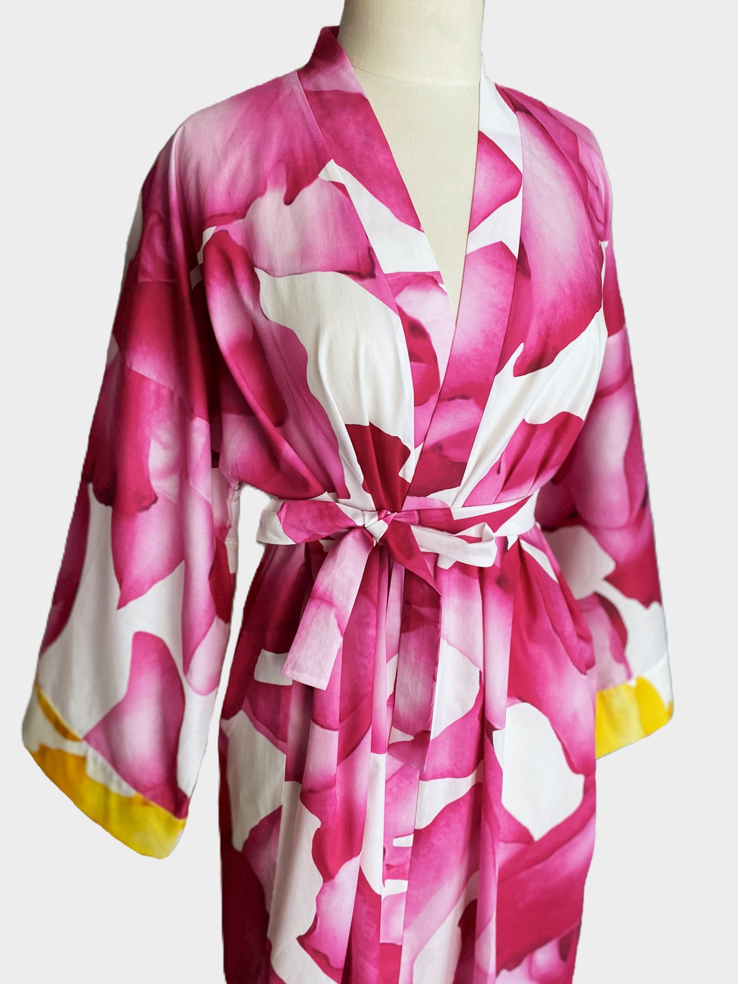 Kimono en batiste de coton blanc aux motifs de pétales roses, ceinture assortie et finitions raffinées.