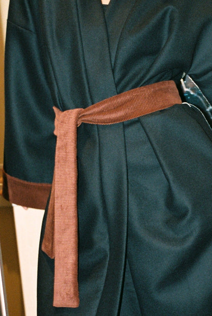 Personne portant le kimono long COLBERT Atelier Sarita en laine caviar noire avec finitions en velours coton couleur oud. Modèle ample et architectural, confectionné à la main à Paris, pensé comme un manteau kimono hivernal unisexe.