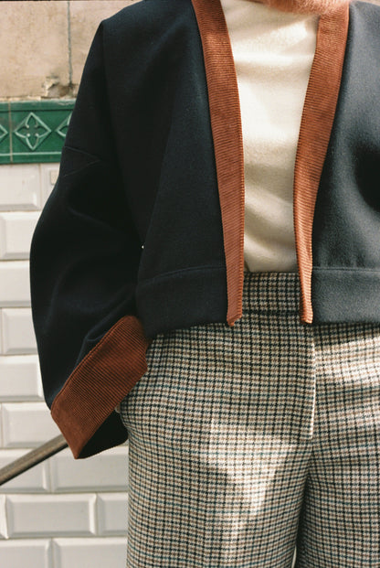 Femme portant le kimono VÉRO Atelier Sarita, un kimono court en laine noire caviar avec finitions en velours coton couleur oud, photographié dans une entrée de métro parisien. Modèle au style architectural et urbain, confectionné à la main à Paris.