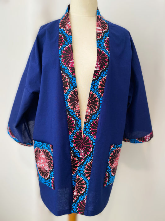 Ce kimono court allie la sobriété du coton bleu à l’éclat des motifs en wax pour une pièce unique et vibrante. Fabriqué avec soin, ce kimono est un véritable hommage au mélange des cultures et au savoir-faire artisanal.