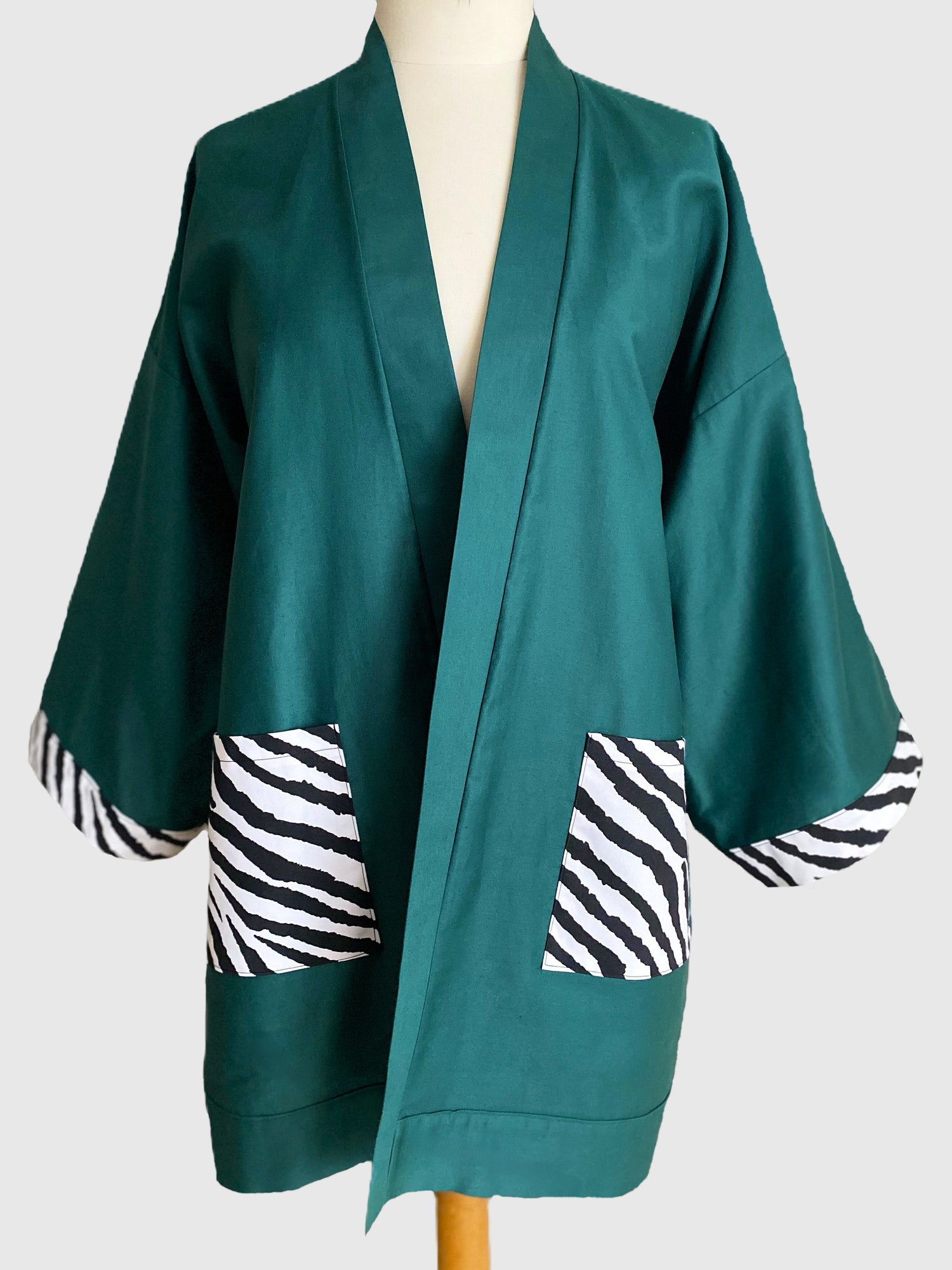 Kimono en coton vert avec poches et revers de manches au motif zèbre, confectionné à la main à Paris. Pièce unique, coupe ample et fluide, idéale pour un look chic et décontracté.