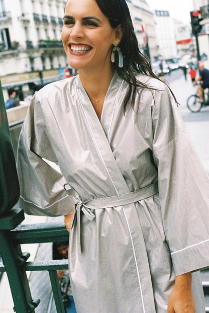 Atelier Sarita – Kimono Crystal en popeline de coton argenté. Long kimono fluide à la coupe affirmée, ceinturé à la taille, confectionné à la main à Paris en série limitée. Une pièce audacieuse et urbaine, inspirée des reflets minéraux et des lumières de l’architecture parisienne