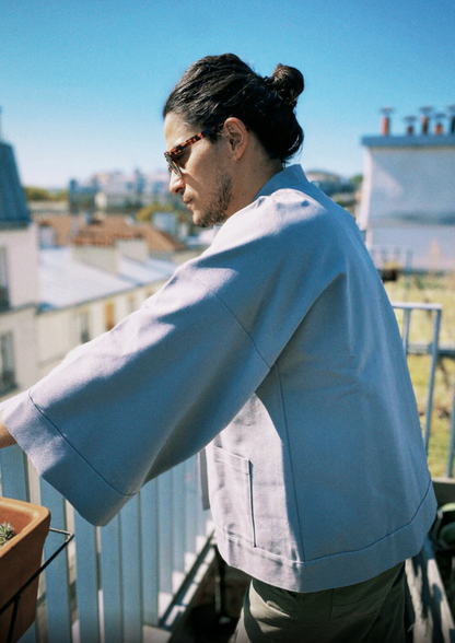 Homme portant un kimono gris en coton biologique, coupe ample avec ceinture. Pièce confectionnée à la main à Paris, par Atelier Sarita.
