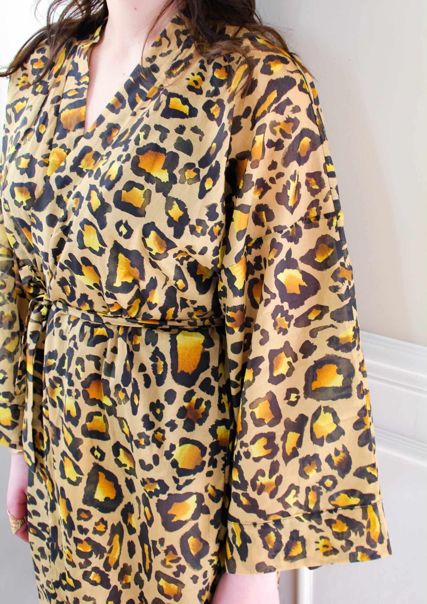 Femme portant un kimono long en voile de coton motif léopard, noué à la taille, dans une pièce lumineuse.