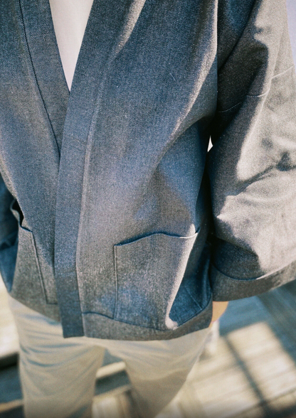 Homme portant un kimono court en denim noir 100% coton, avec manches larges et poches plaquées, fait à la main à Paris. 