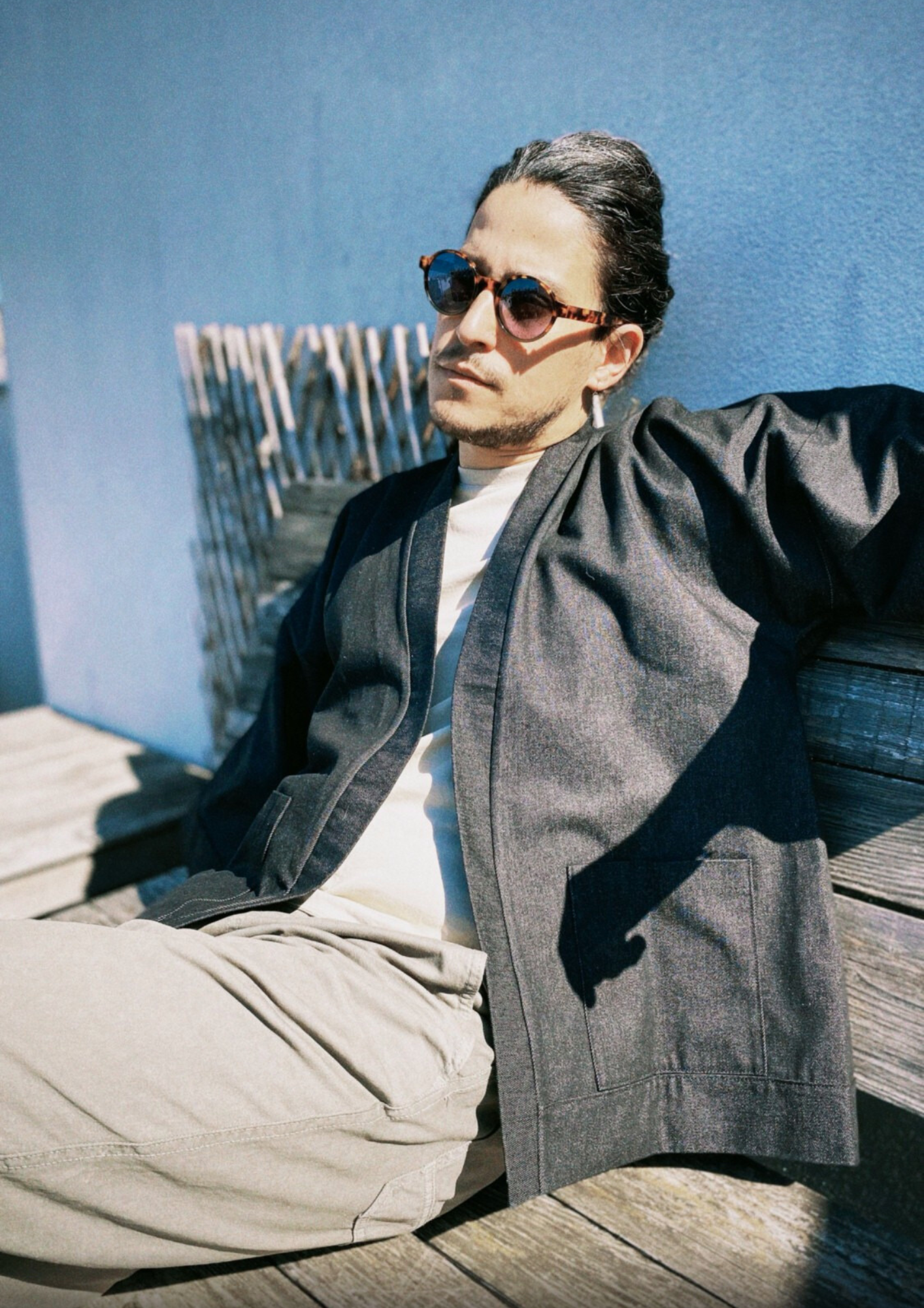 Homme portant un kimono court en denim noir 100% coton, avec manches larges et poches plaquées, fait à la main à Paris. 