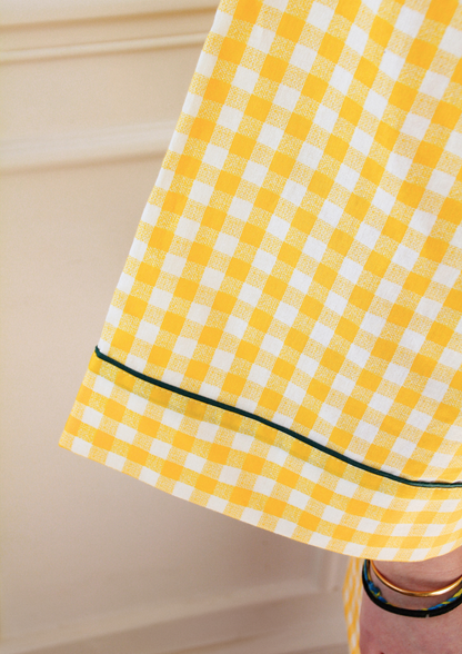 Femme portant un kimono court en coton vichy jaune à passepoil vert, noué à la taille, dans une pièce lumineuse.