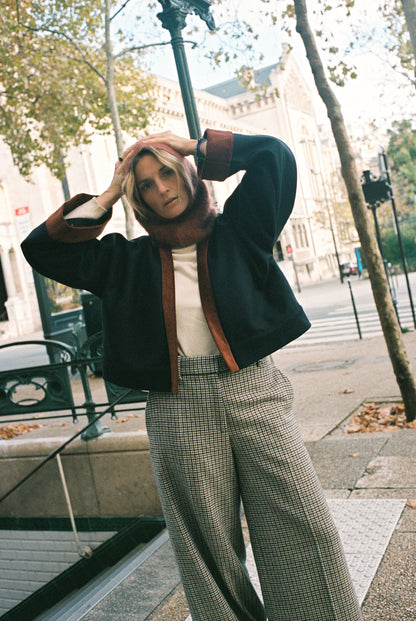 Femme portant le kimono VÉRO Atelier Sarita, un kimono court en laine noire caviar avec finitions en velours coton couleur oud, photographié dans une entrée de métro parisien. Modèle au style architectural et urbain, confectionné à la main à Paris.