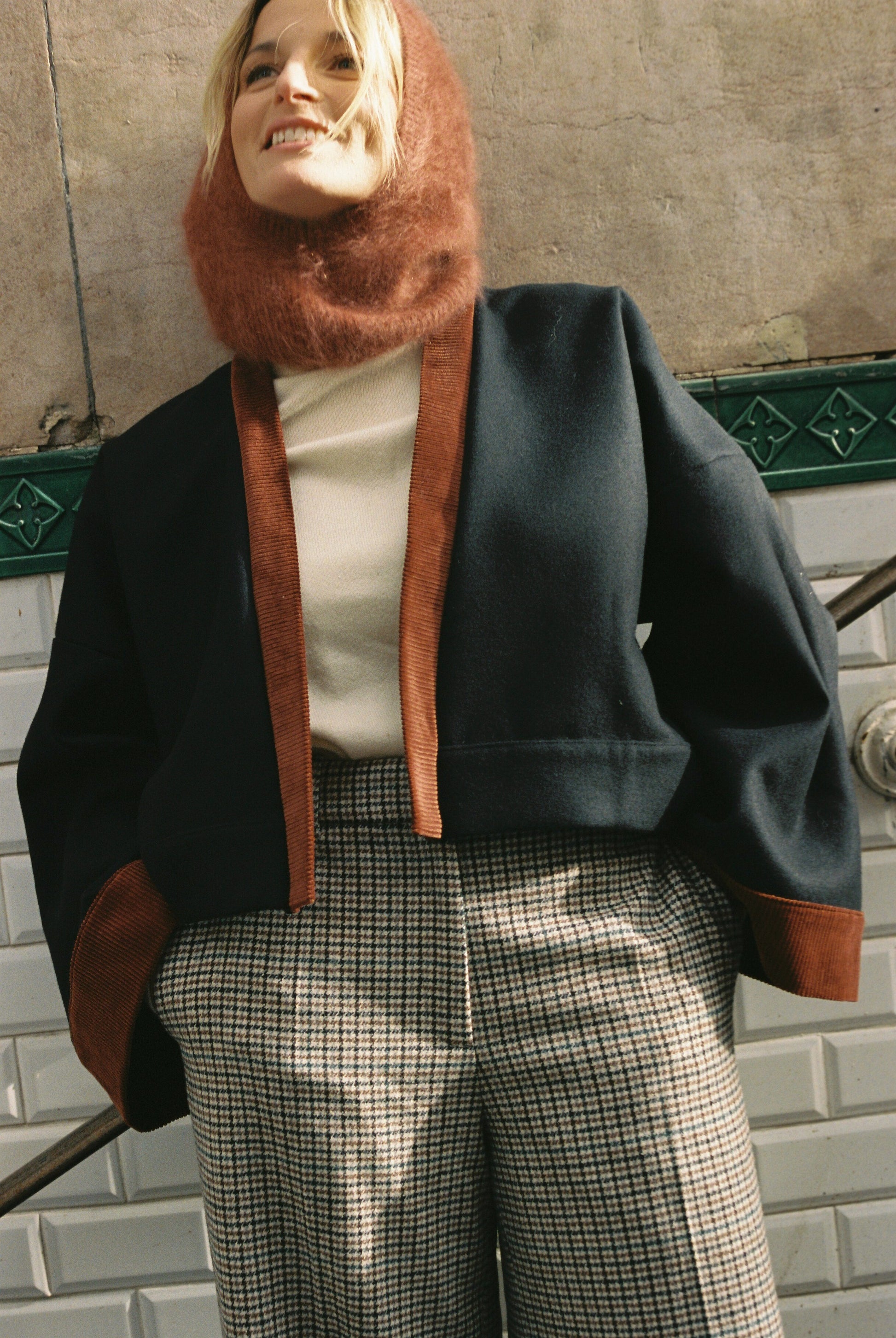 Femme portant le kimono VÉRO Atelier Sarita, un kimono court en laine noire caviar avec finitions en velours coton couleur oud, photographié dans une entrée de métro parisien. Modèle au style architectural et urbain, confectionné à la main à Paris.