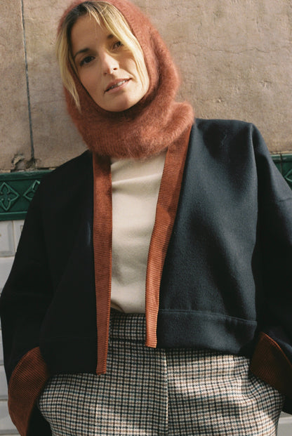 Femme portant le kimono VÉRO Atelier Sarita, un kimono court en laine noire caviar avec finitions en velours coton couleur oud, photographié dans une entrée de métro parisien. Modèle au style architectural et urbain, confectionné à la main à Paris.