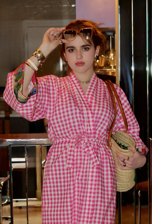Jeune femme portant un kimono long en coton vichy rose et blanc avec ceinture assortie, confectionné à la main, à Paris. Modèle élégant et fluide, idéal pour un style décontracté ou sophistiqué.