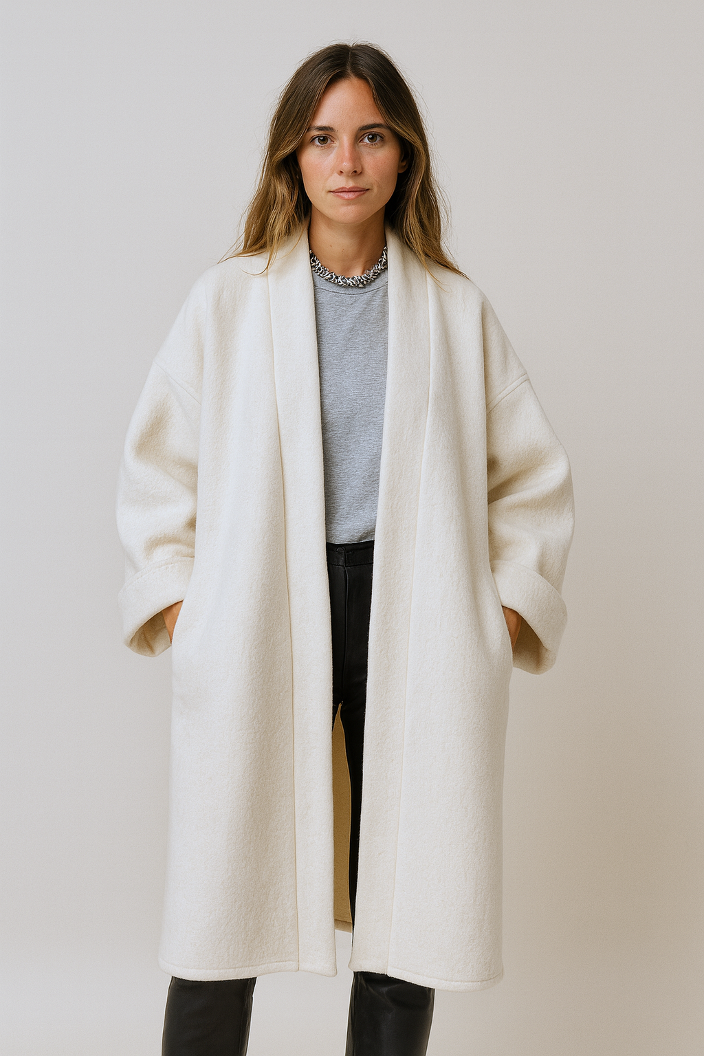 Femme portant un manteau kimono long en laine blanche. Une pièce élégante et contemporaine, fabriquée à la main, à Paris, en série très limitée. 