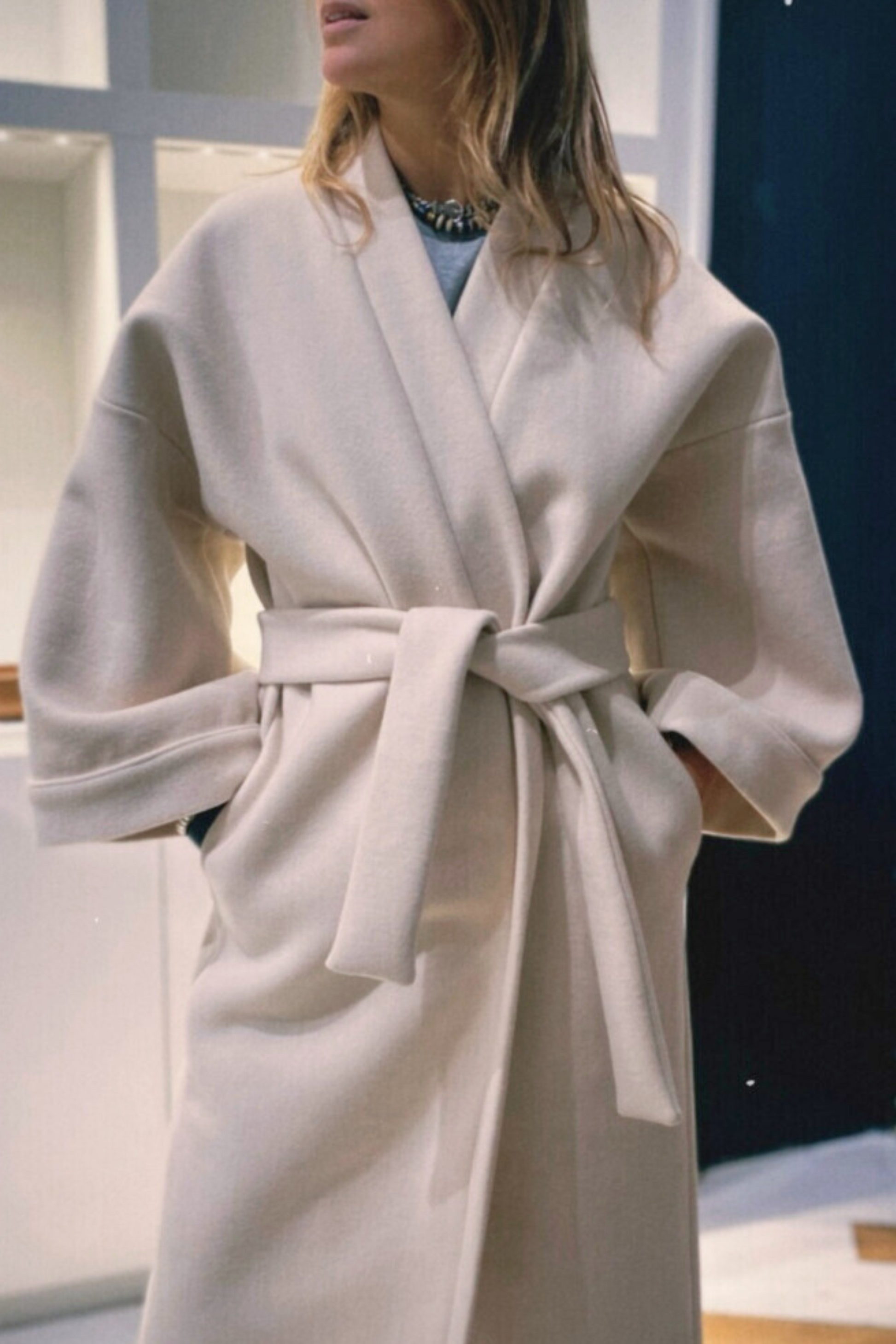 Femme portant un manteau kimono long en laine blanche. Une pièce élégante et contemporaine, fabriquée à la main, à Paris, en série très limitée. 