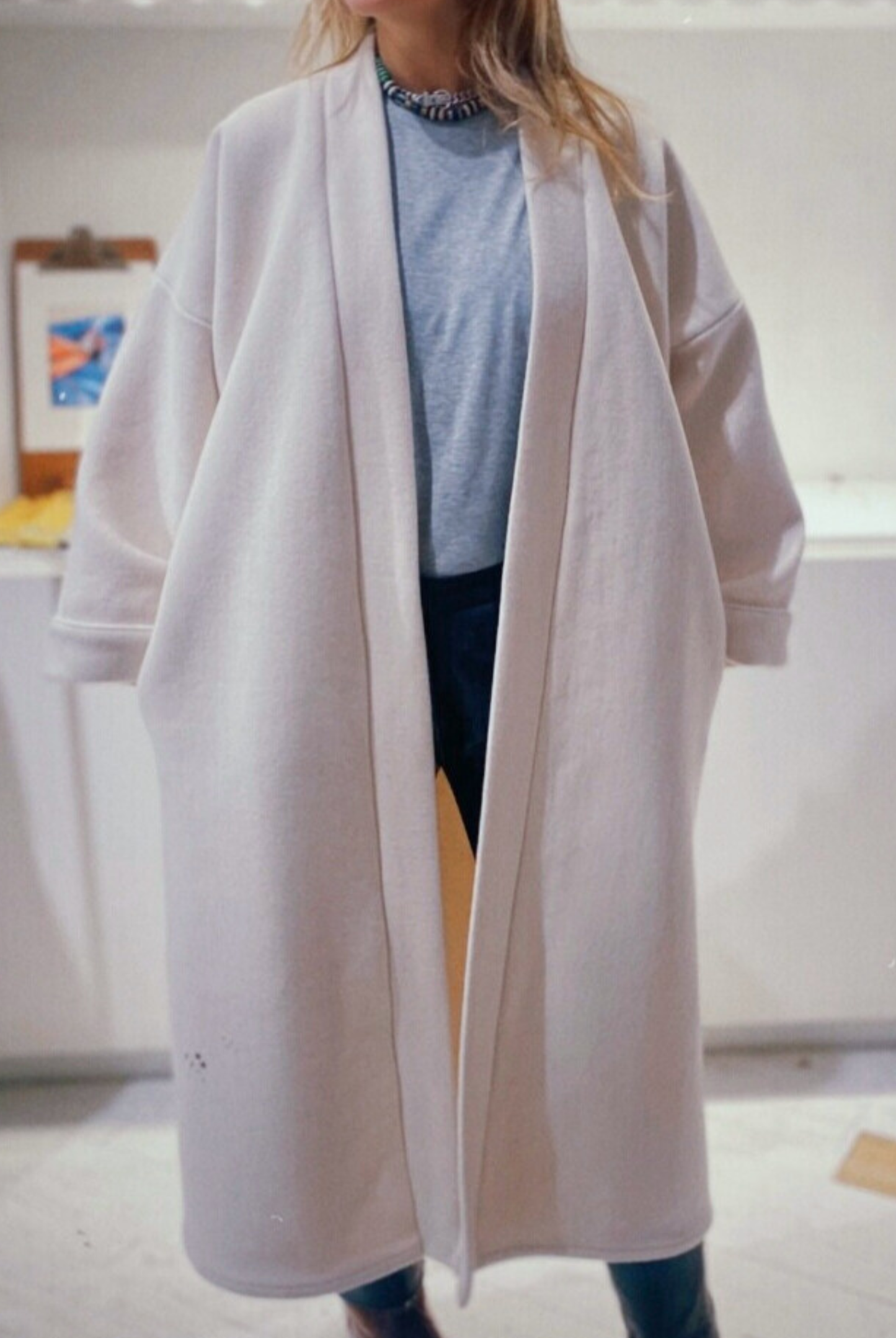 Femme portant un manteau kimono long en laine blanche. Une pièce élégante et contemporaine, fabriquée à la main, à Paris, en série très limitée. 