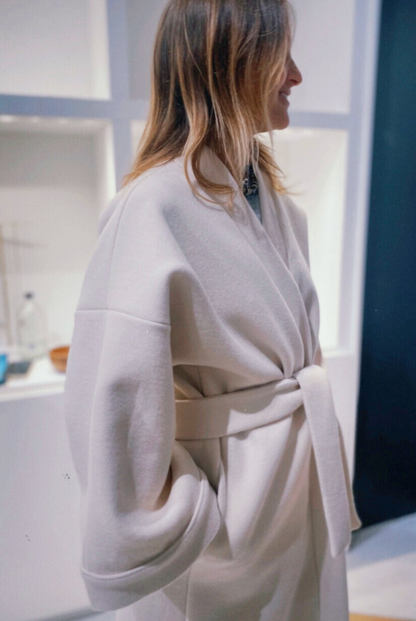 Femme portant un manteau kimono long en laine blanche. Une pièce élégante et contemporaine, fabriquée à la main, à Paris, en série très limitée. 