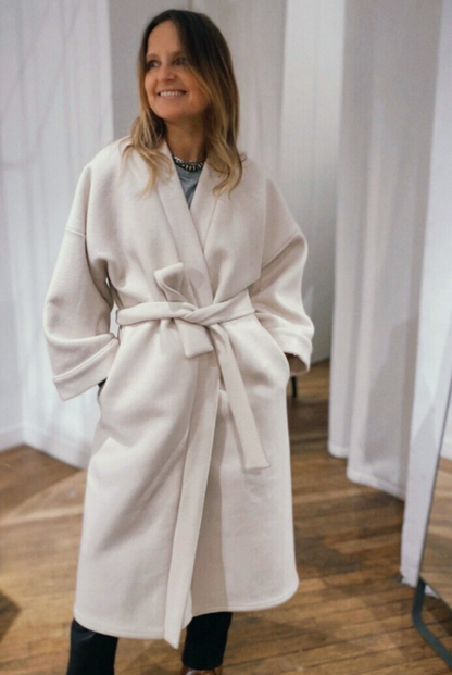Femme portant un manteau kimono long en laine blanche. Une pièce élégante et contemporaine, fabriquée à la main, à Paris, en série très limitée. 