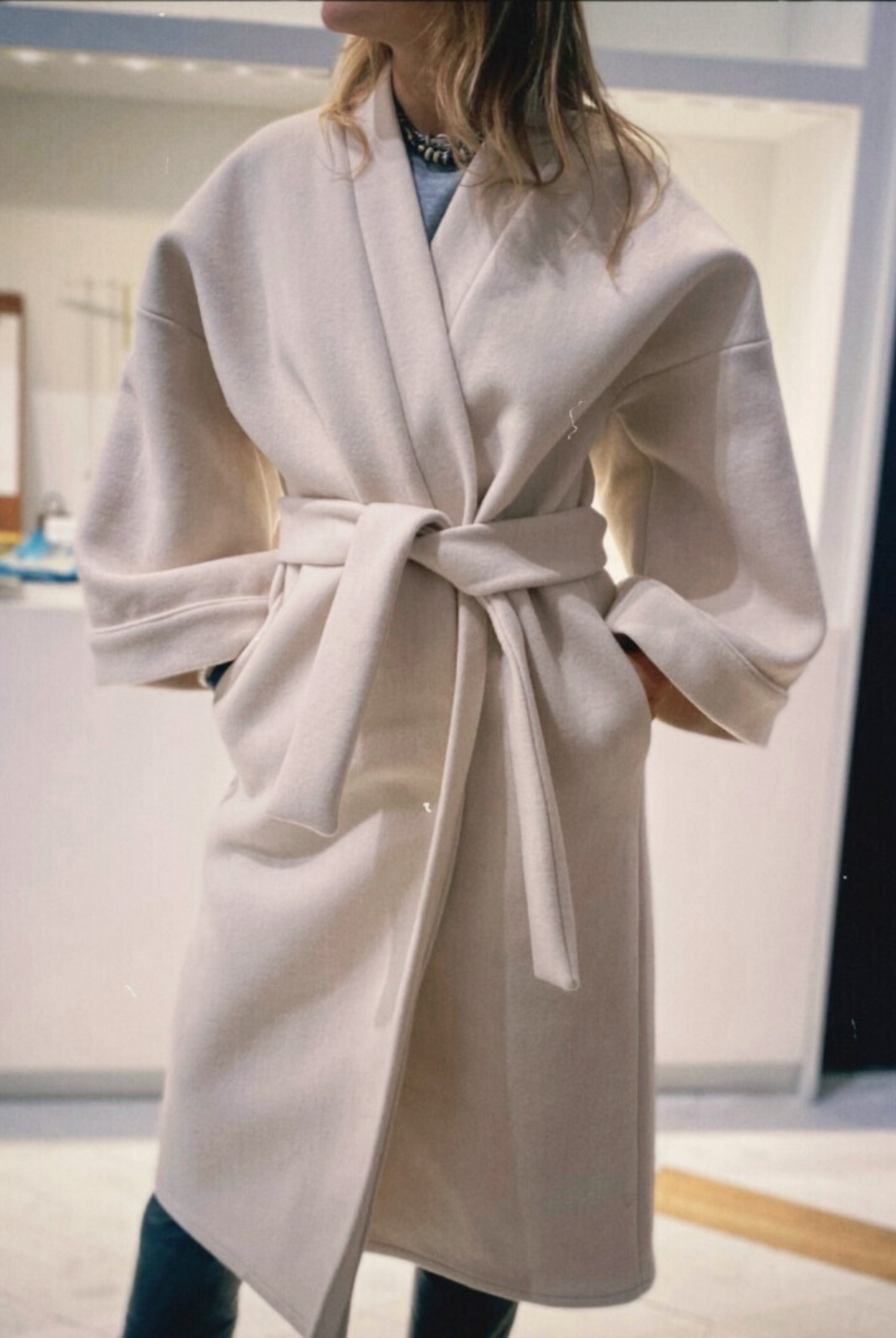 Femme portant un manteau kimono long en laine blanche. Une pièce élégante et contemporaine, fabriquée à la main, à Paris, en série très limitée. 