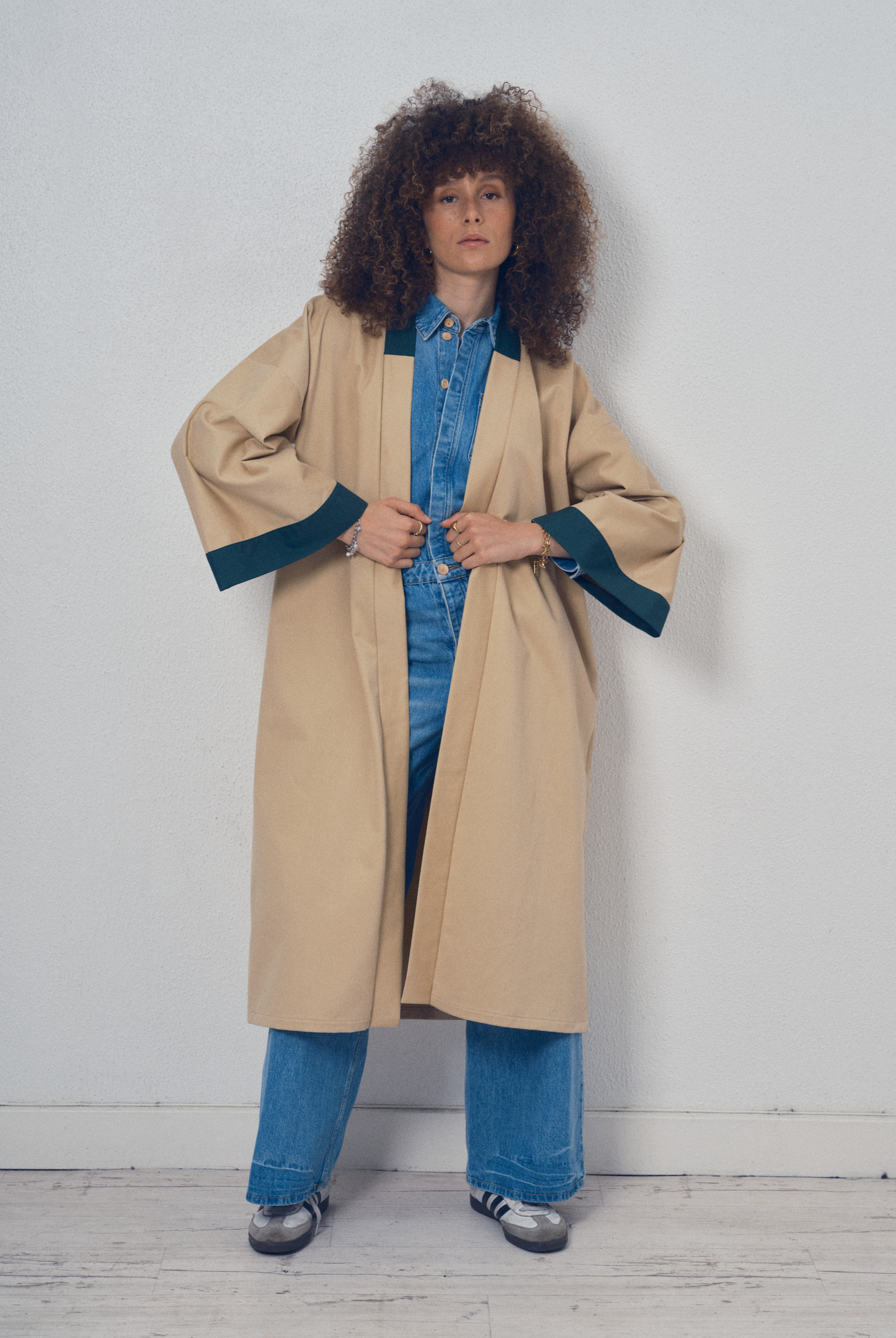 Trench beige aux lignes kimono avec finitions vert foncé porté ceinturé, modèle Charlot de la collection Côté Marais par Atelier Sarita.