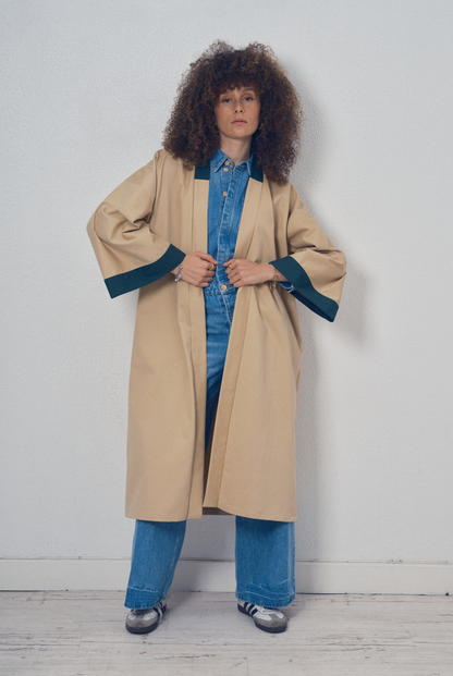 Trench beige aux lignes kimono avec finitions vert foncé porté ceinturé, modèle Charlot de la collection Côté Marais par Atelier Sarita.