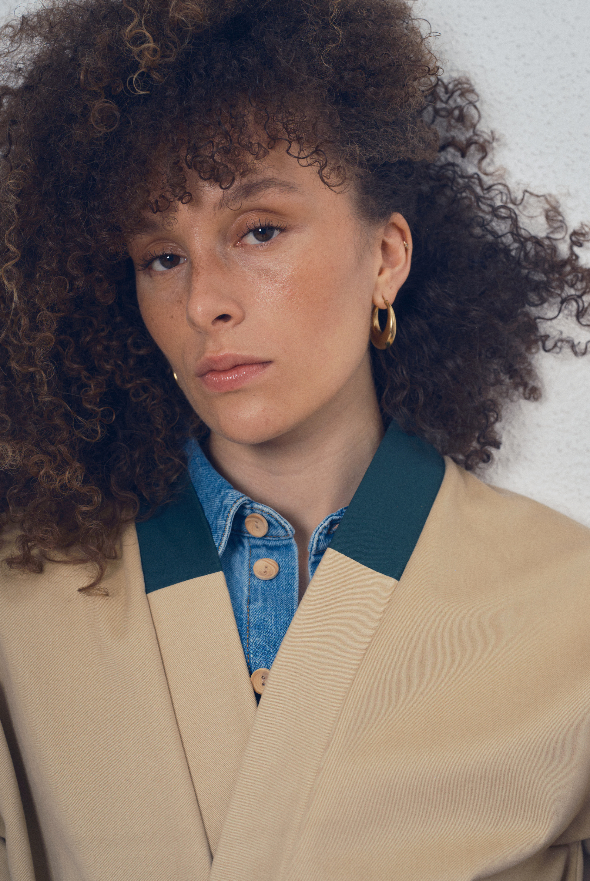 Trench beige aux lignes kimono avec finitions vert foncé porté ceinturé, modèle Charlot de la collection Côté Marais par Atelier Sarita.