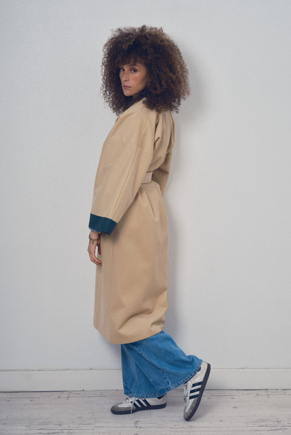 Trench beige aux lignes kimono avec finitions vert foncé porté ceinturé, modèle Charlot de la collection Côté Marais par Atelier Sarita.