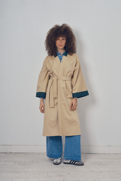 Trench beige aux lignes kimono avec finitions vert foncé porté ceinturé, modèle Charlot de la collection Côté Marais par Atelier Sarita.