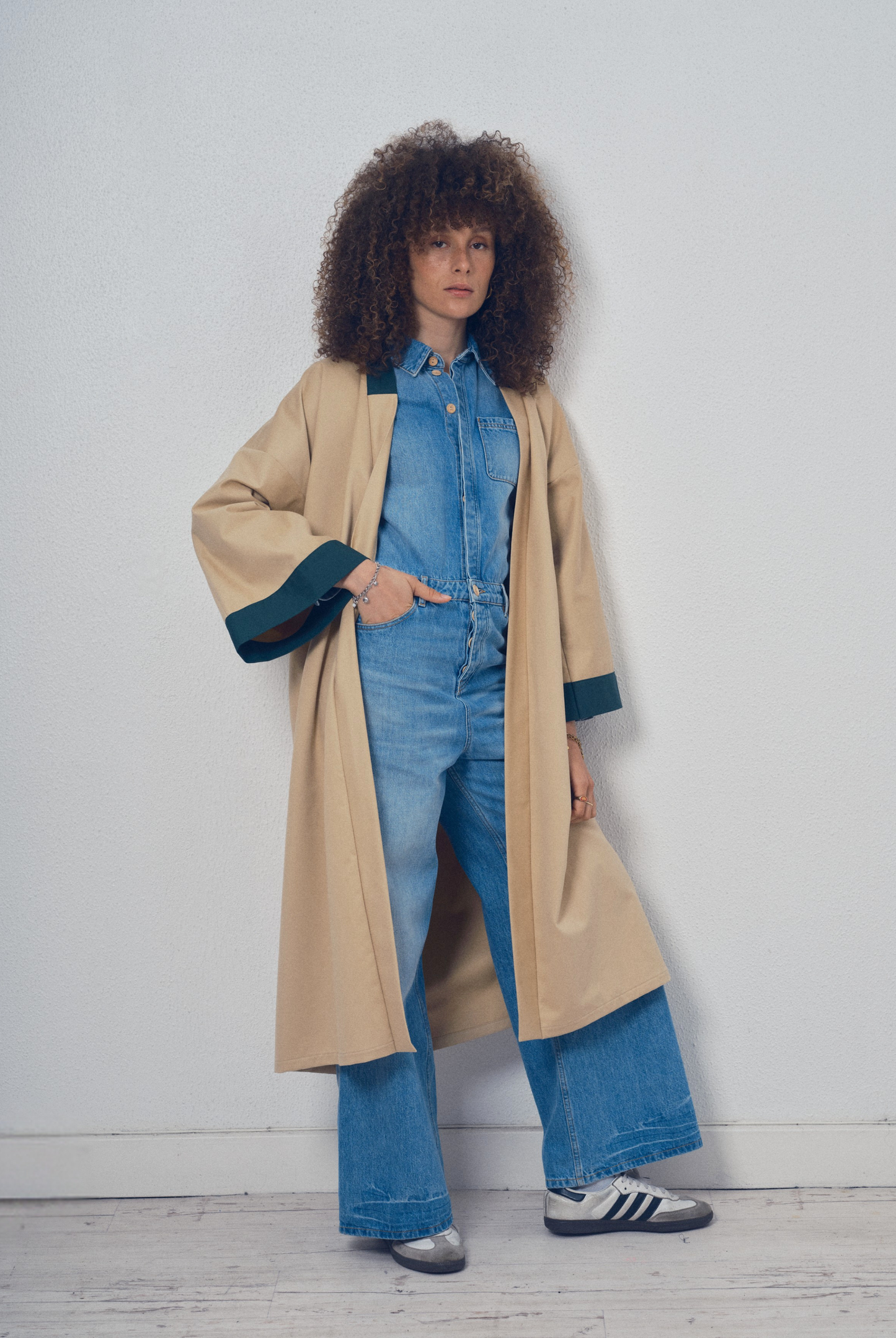 Trench beige aux lignes kimono avec finitions vert foncé porté ceinturé, modèle Charlot de la collection Côté Marais par Atelier Sarita.
