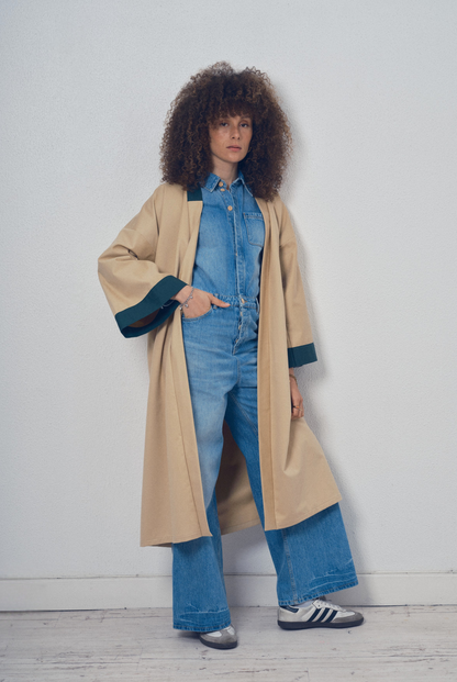 Trench beige aux lignes kimono avec finitions vert foncé porté ceinturé, modèle Charlot de la collection Côté Marais par Atelier Sarita.