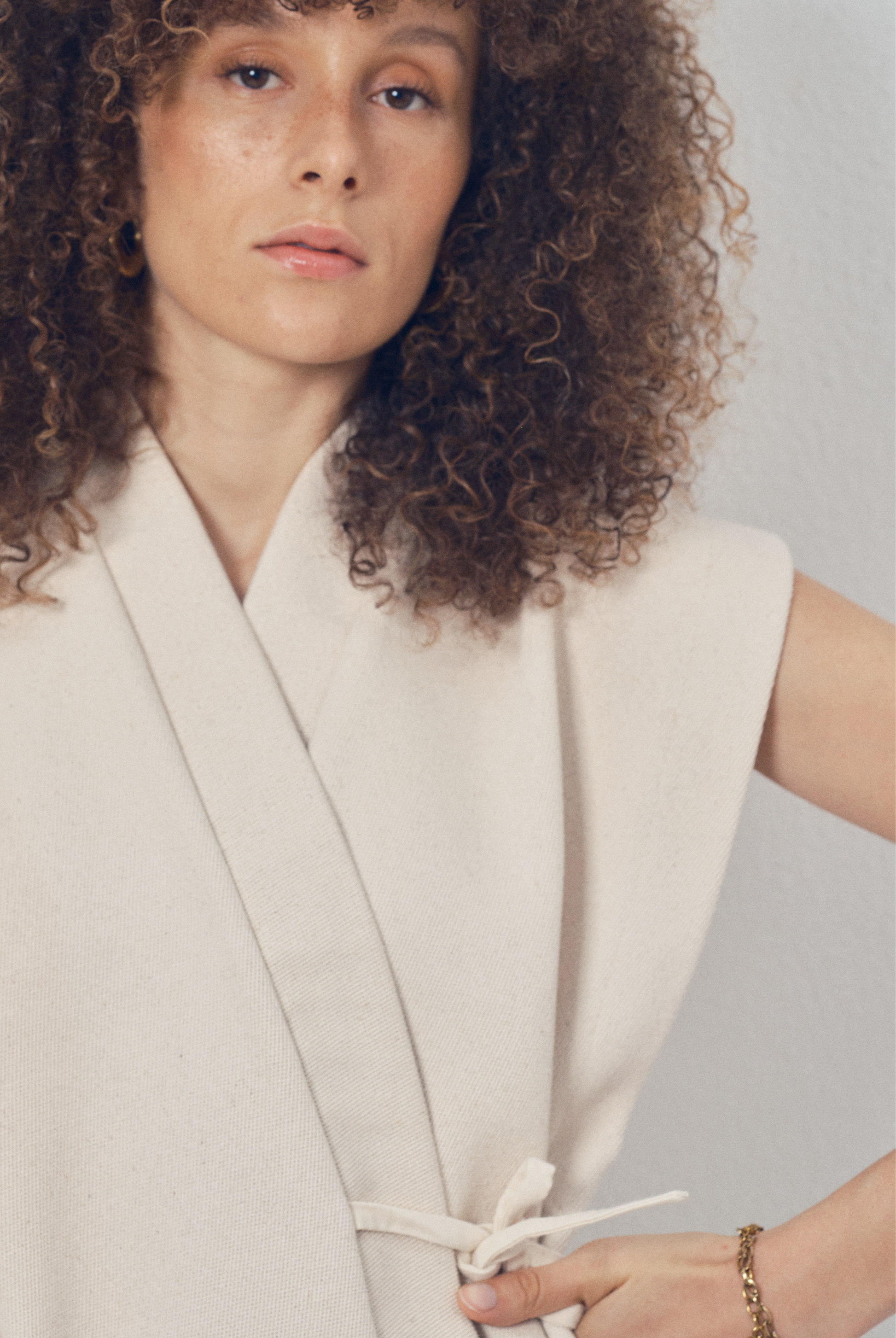 Pièce sans manches écrue aux lignes kimono portée sur un pantalon ample beige, modèle Claude de la collection Côté Marais par Atelier Sarita