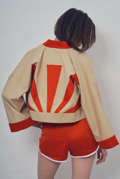 Veste crop beige et rouge aux lignes kimono portée avec un short rouge, modèle Gilles de la collection Côté Marais par Atelier Sarita.