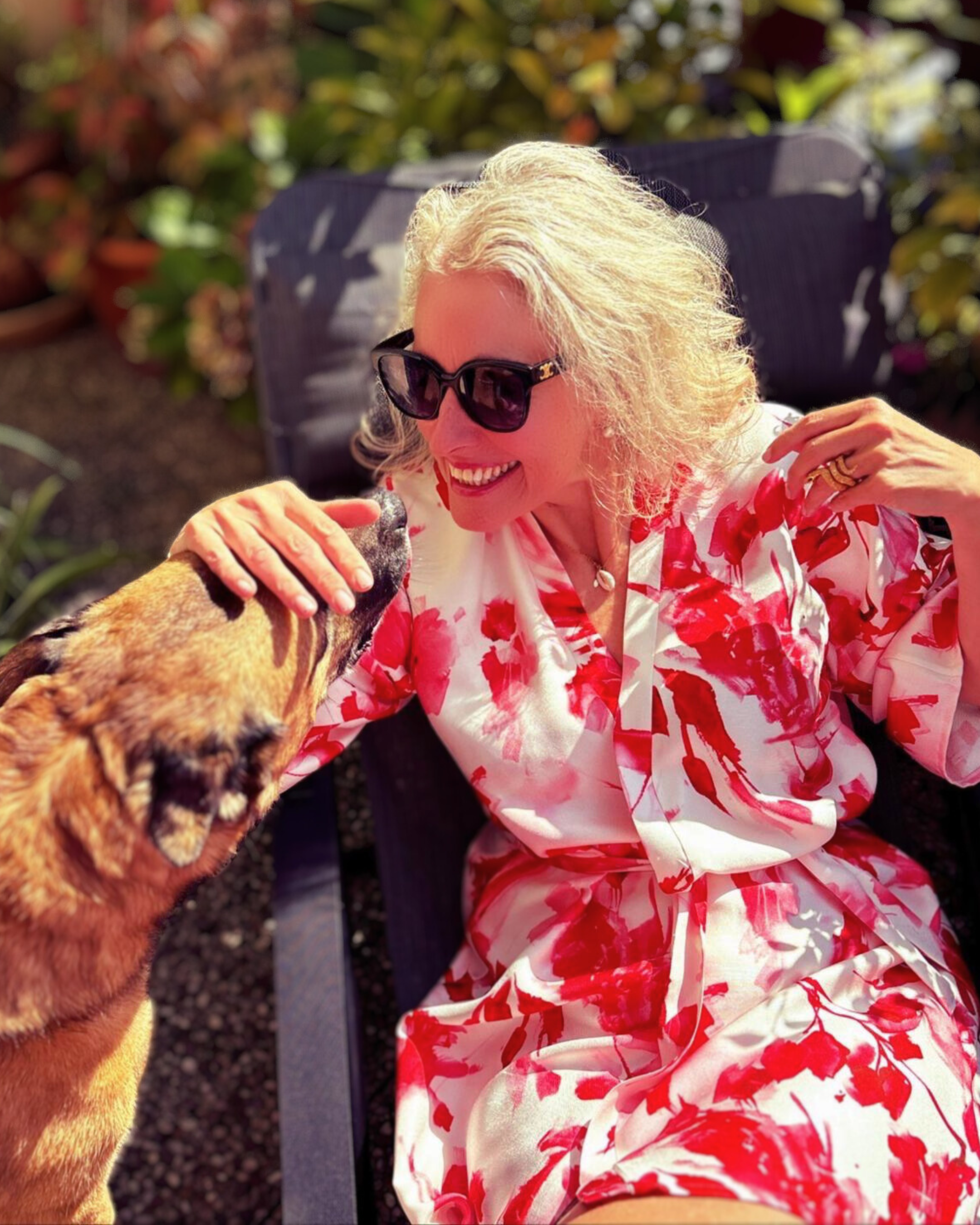 Niki, cliente d'Atelier Sarita heureuse et élégante dans son kimono en soie rouge et blanc fait sur mesure sur sa terrasse en compagnie de son chien. Elle témoigne de l'usage quotidien de son kimono. 