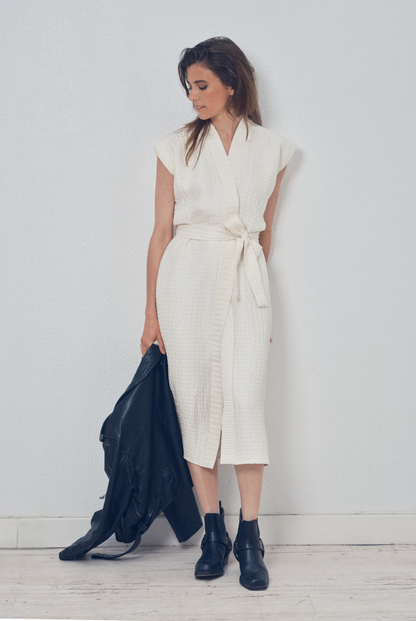 Robe portefeuille blanche en soie texturée portée avec des bottines noires et un perfecto en cuir noir, modèle Pastourelle de la collection Côté Marais par Atelier Sarita.